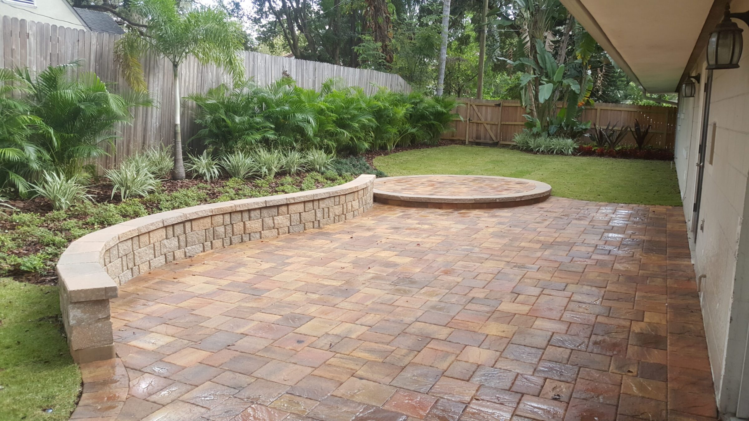 Backyard patio with pavers and lush green garden.