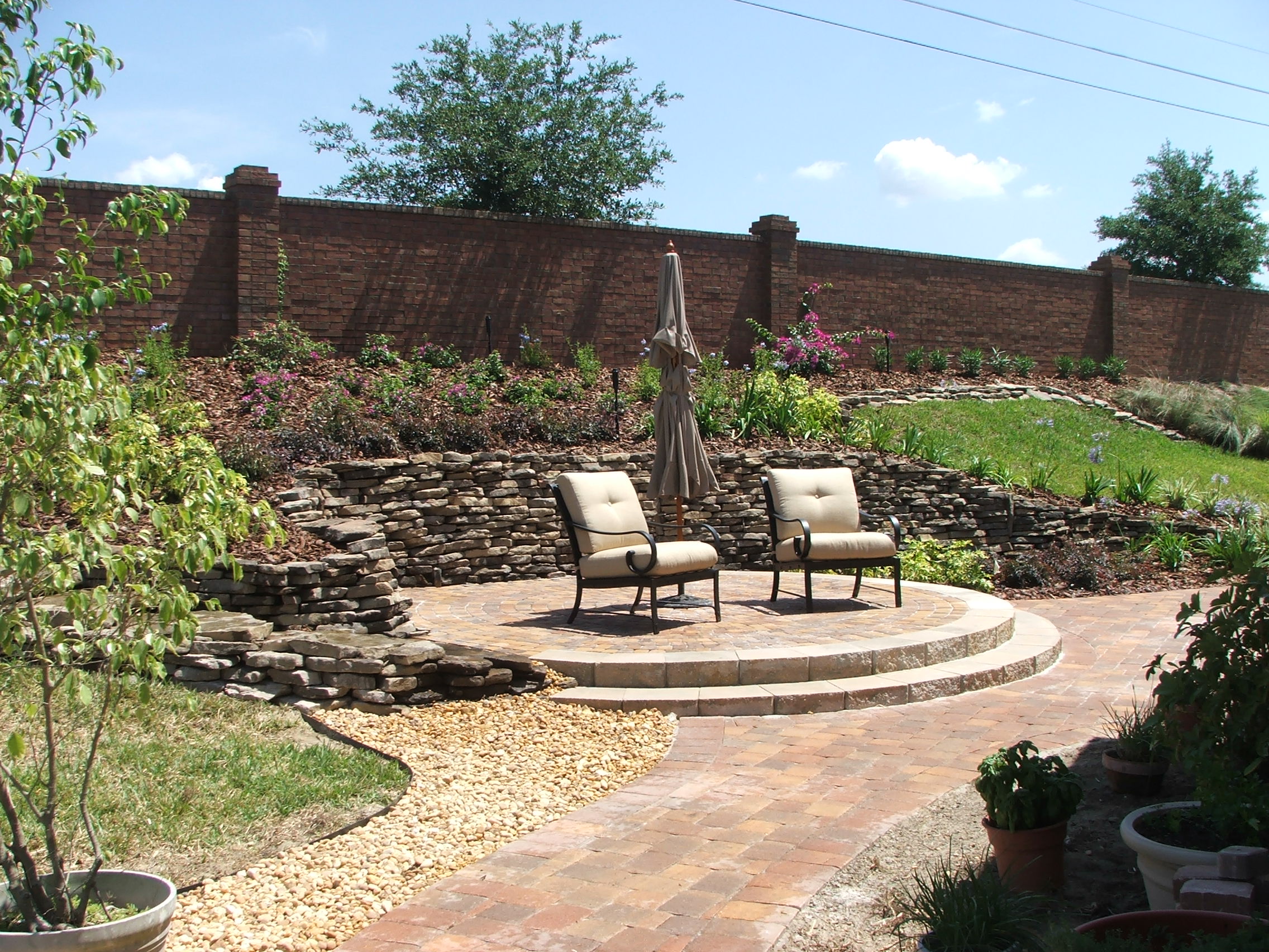 Outdoor patio with chairs, stone wall, and garden.