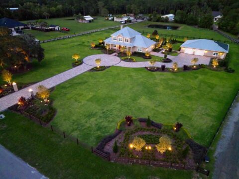 Aerial view of illuminated country house and garden