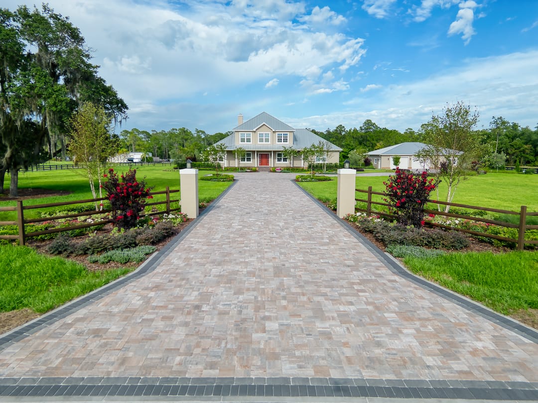 Country home with long paved driveway and gardens.