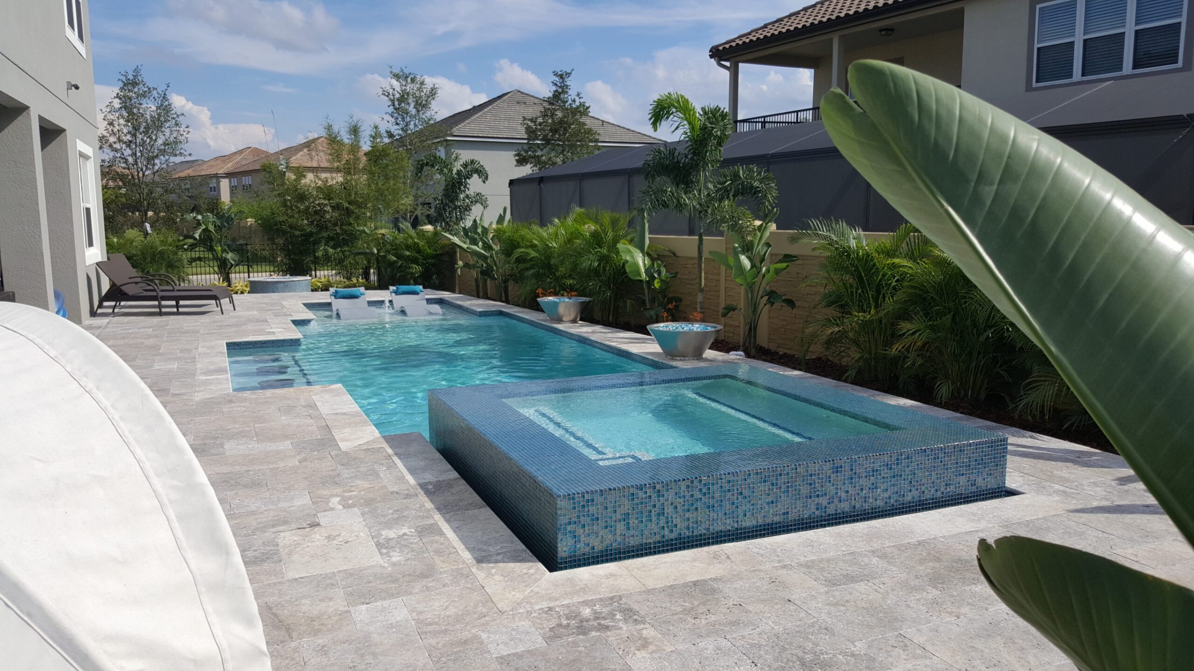 Backyard pool with hot tub and greenery.