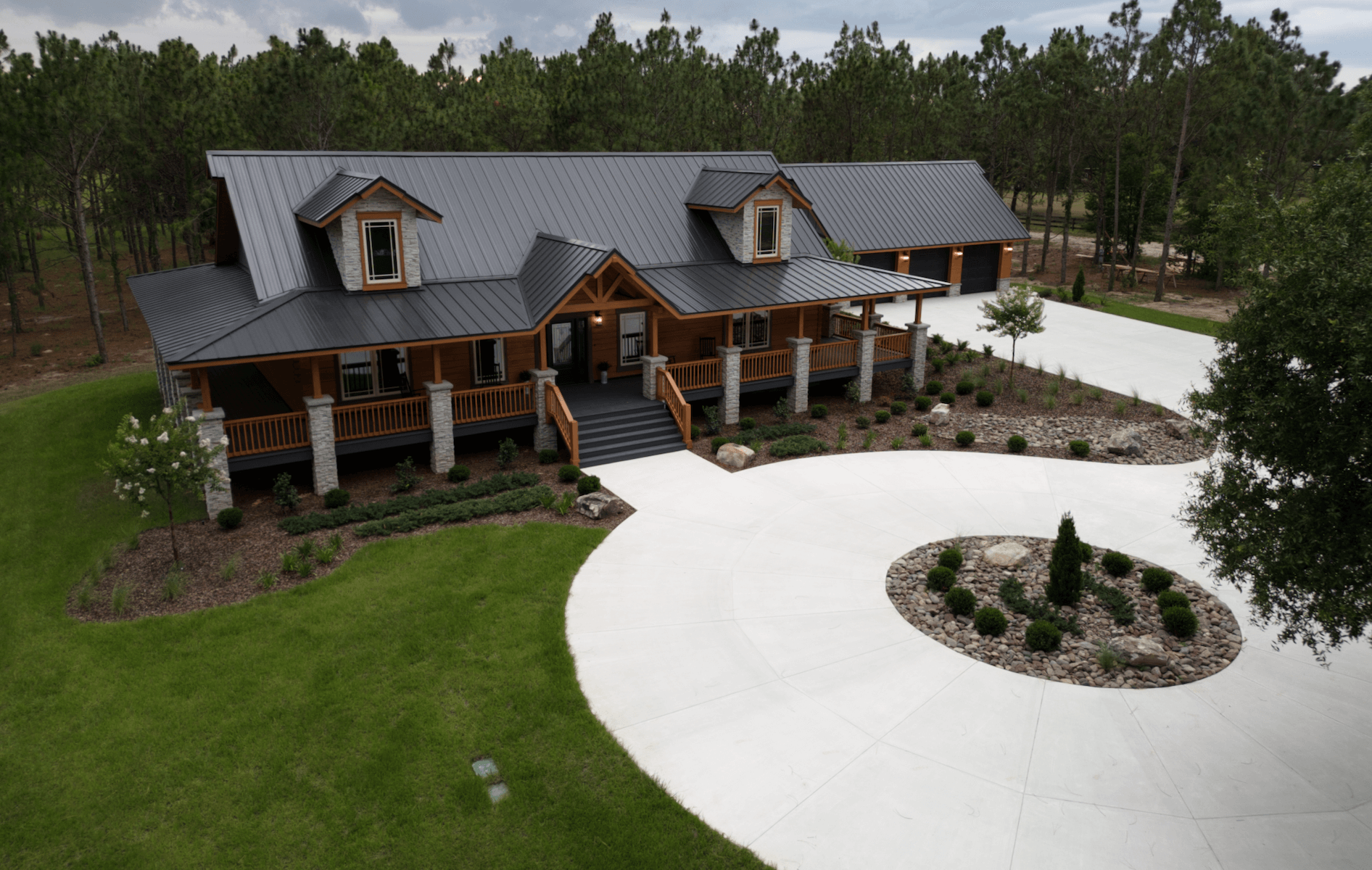 Log cabin with circular driveway and green lawn.