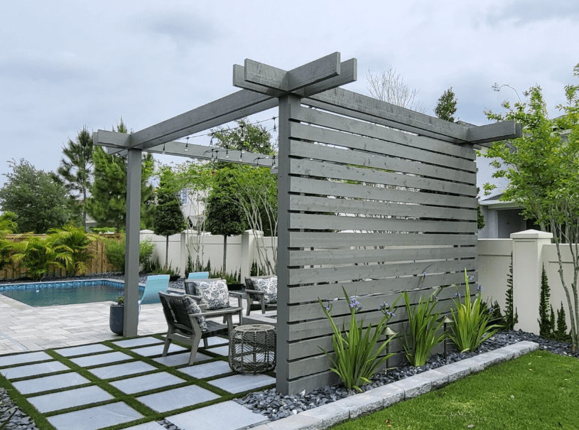 Modern backyard patio with pergola by pool.