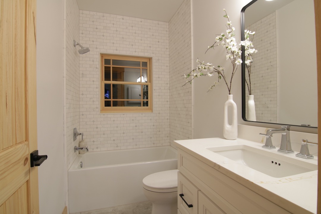 Modern bathroom with white tiles and vanity.