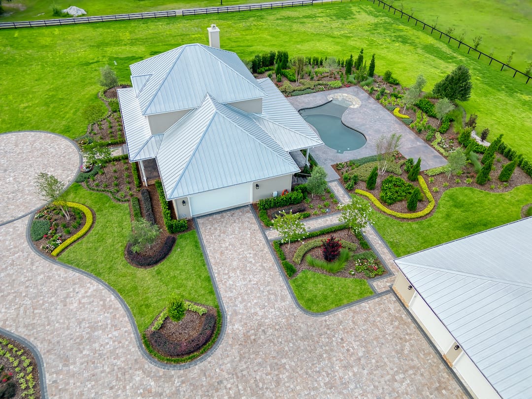 Aerial view of house with landscaped yard and pool.