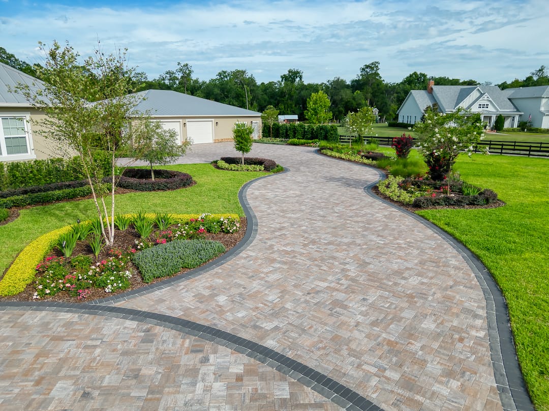 Elegant brick driveway with landscaped garden view.