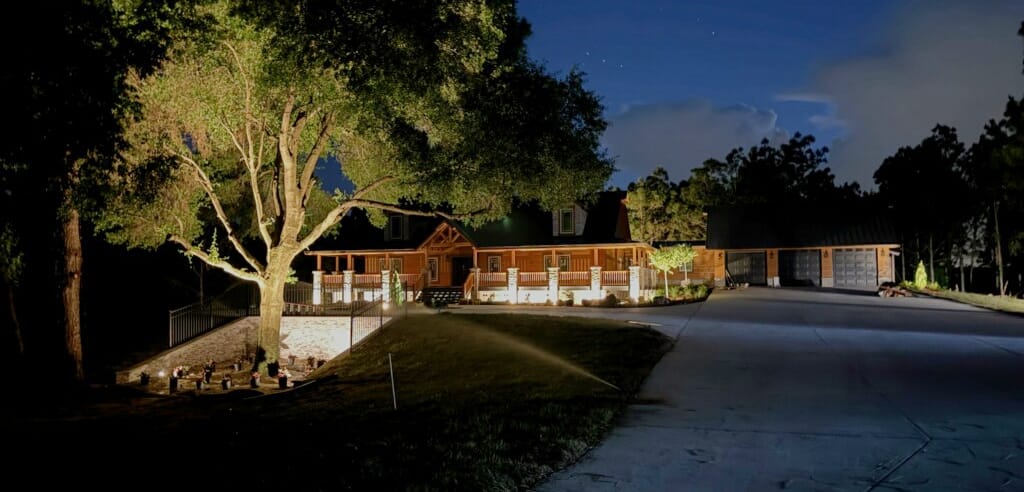 Illuminated house exterior at night with trees.