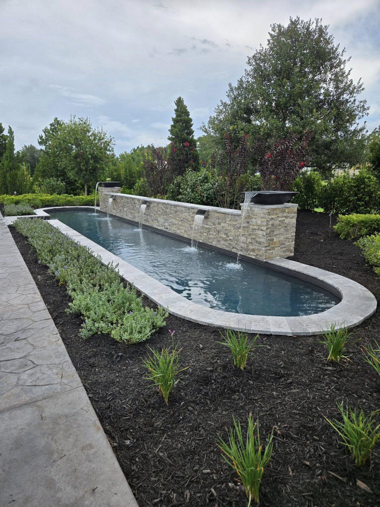 Elegant garden pool with fountains and lush greenery.
