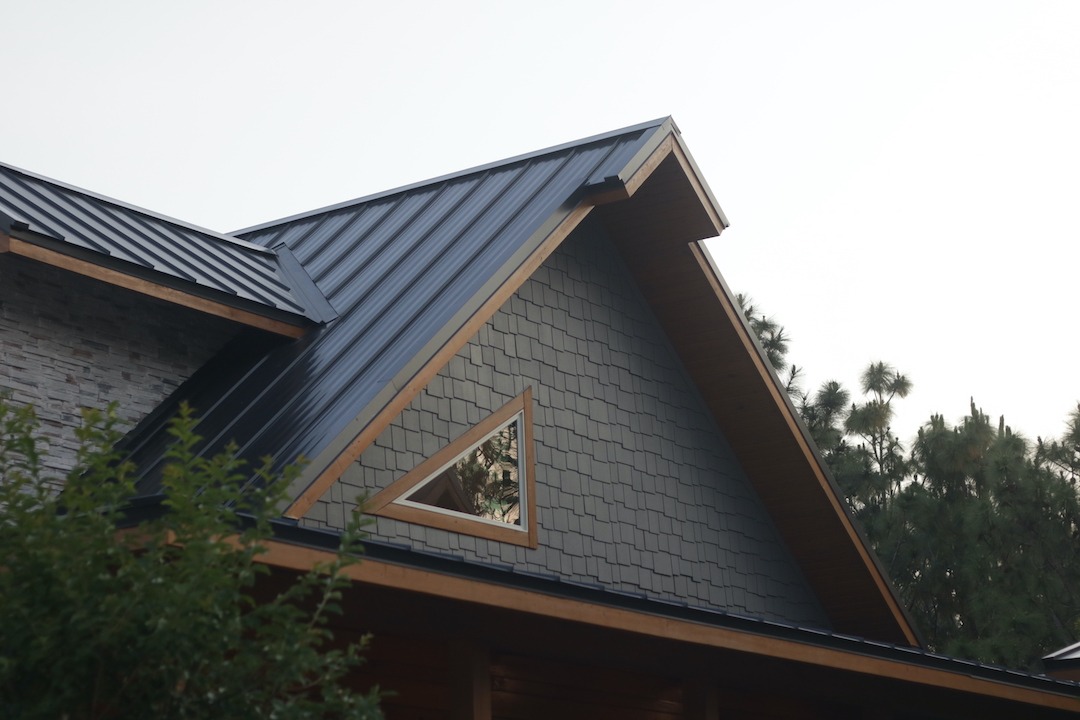 Modern house with metal roof and triangular window.