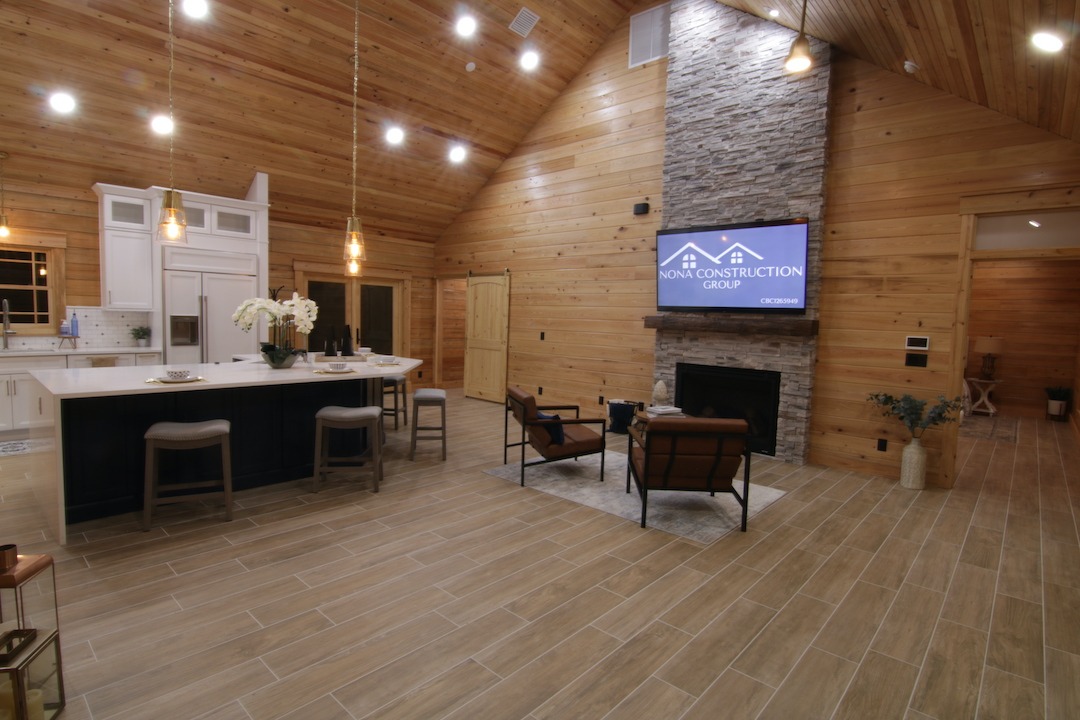 Spacious modern cabin interior with kitchen and fireplace.