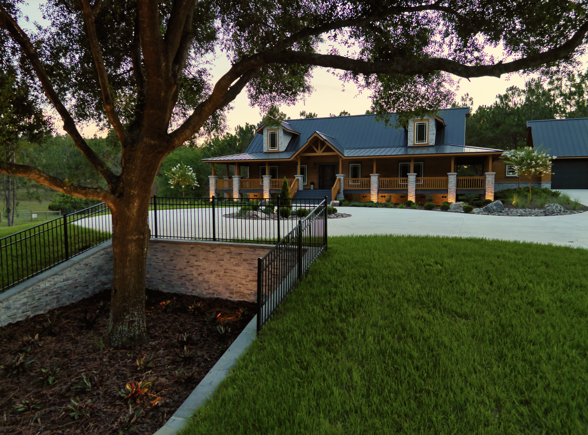 Rustic country house with tree and fenced yard.