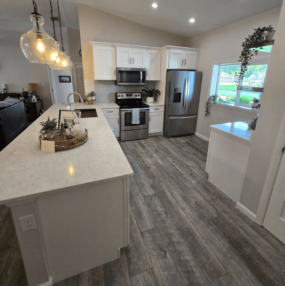 Modern kitchen with white cabinets and wooden floor.