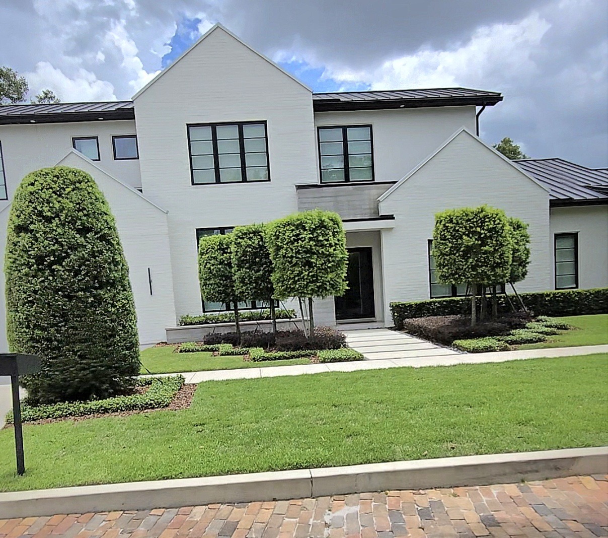 Modern two-story house with manicured lawn and trees.