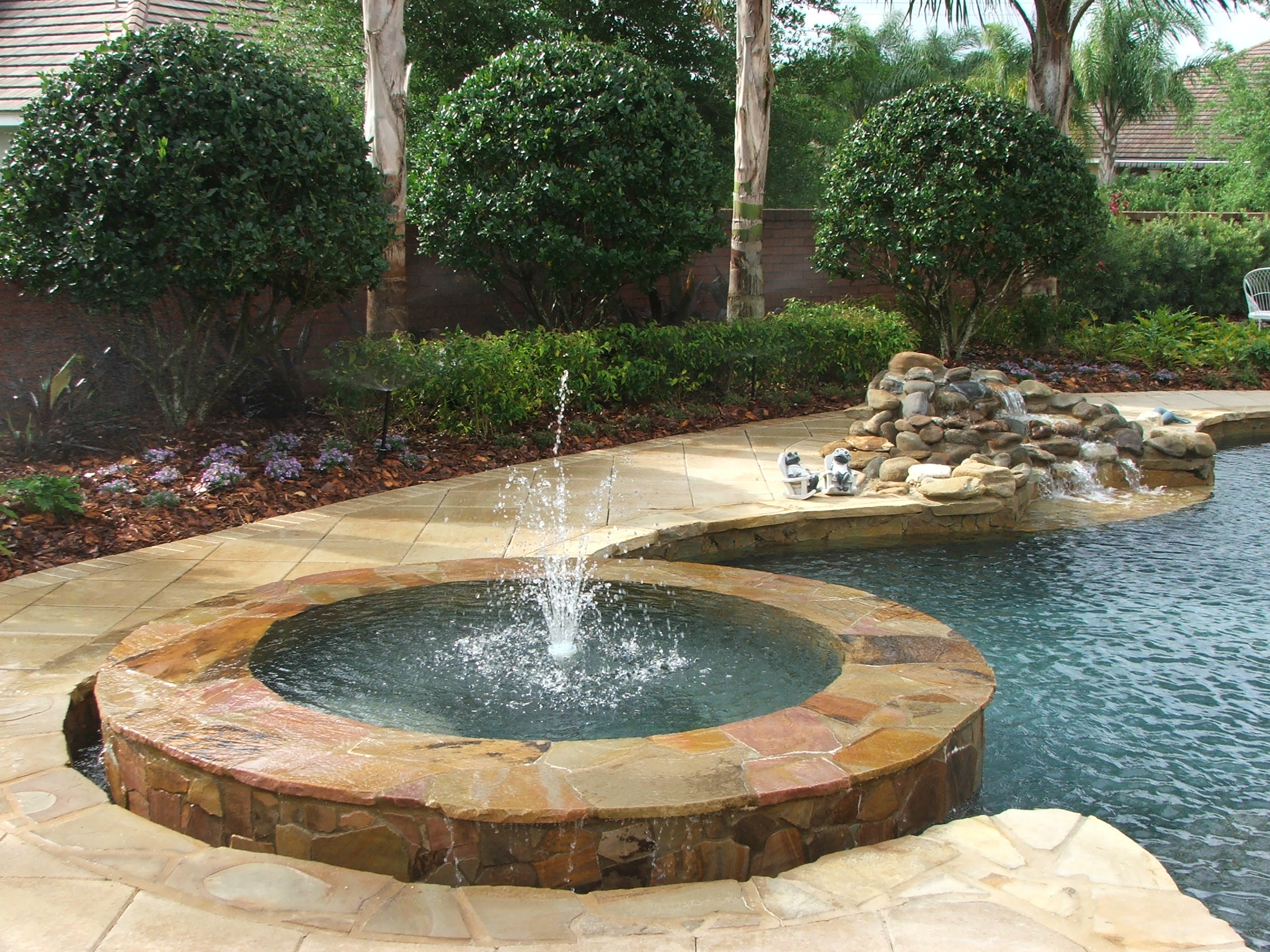 Backyard pool with fountain and stone patio