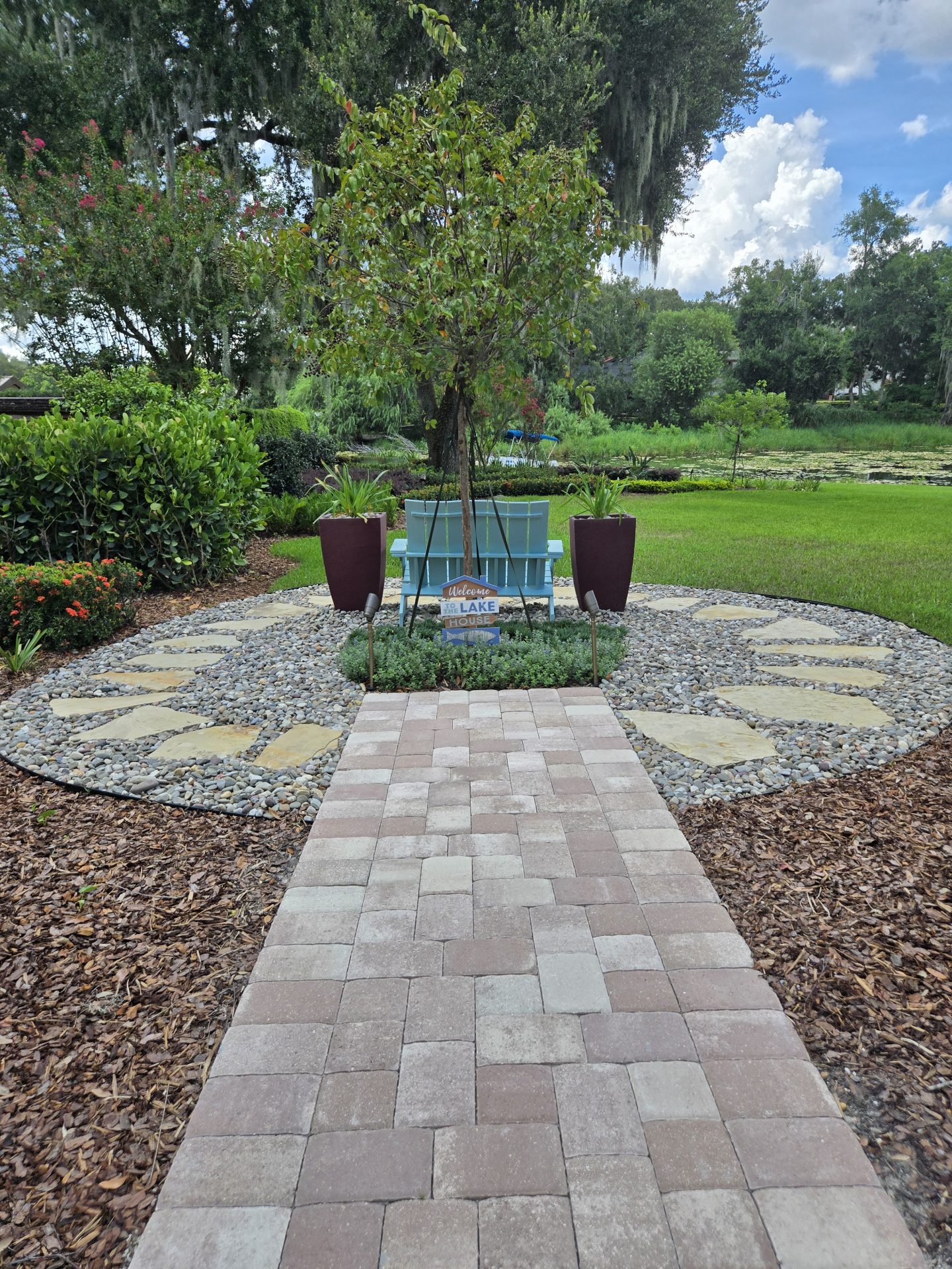 Pathway leads to garden with bench and trees.