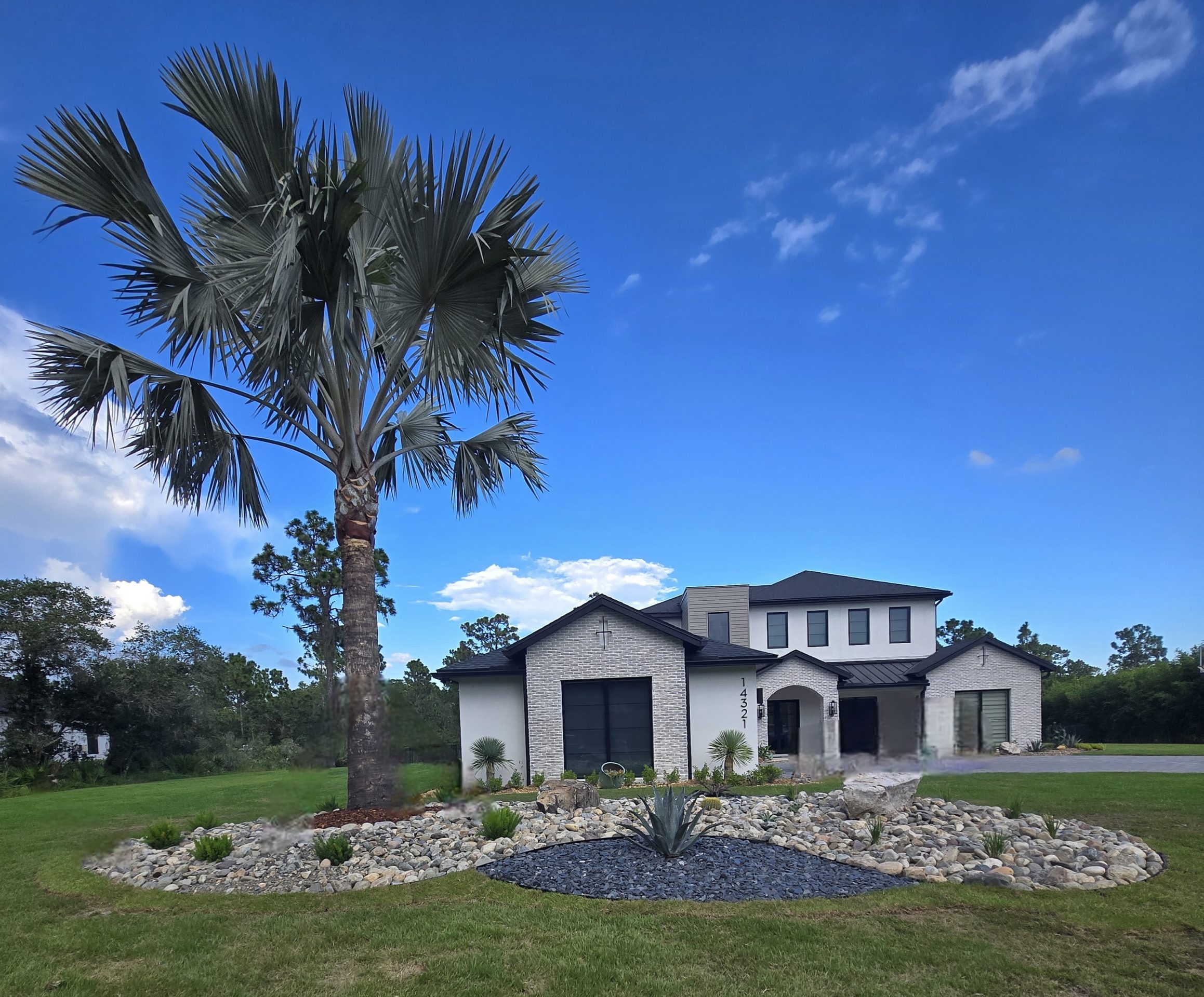 Modern house with palm tree and landscaped yard.