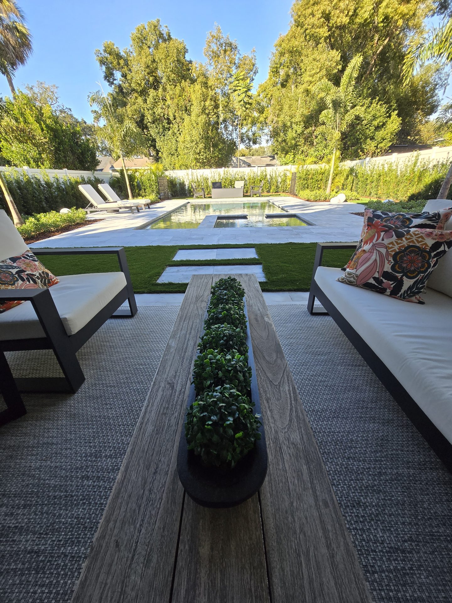 Luxury patio with pool and greenery view.
