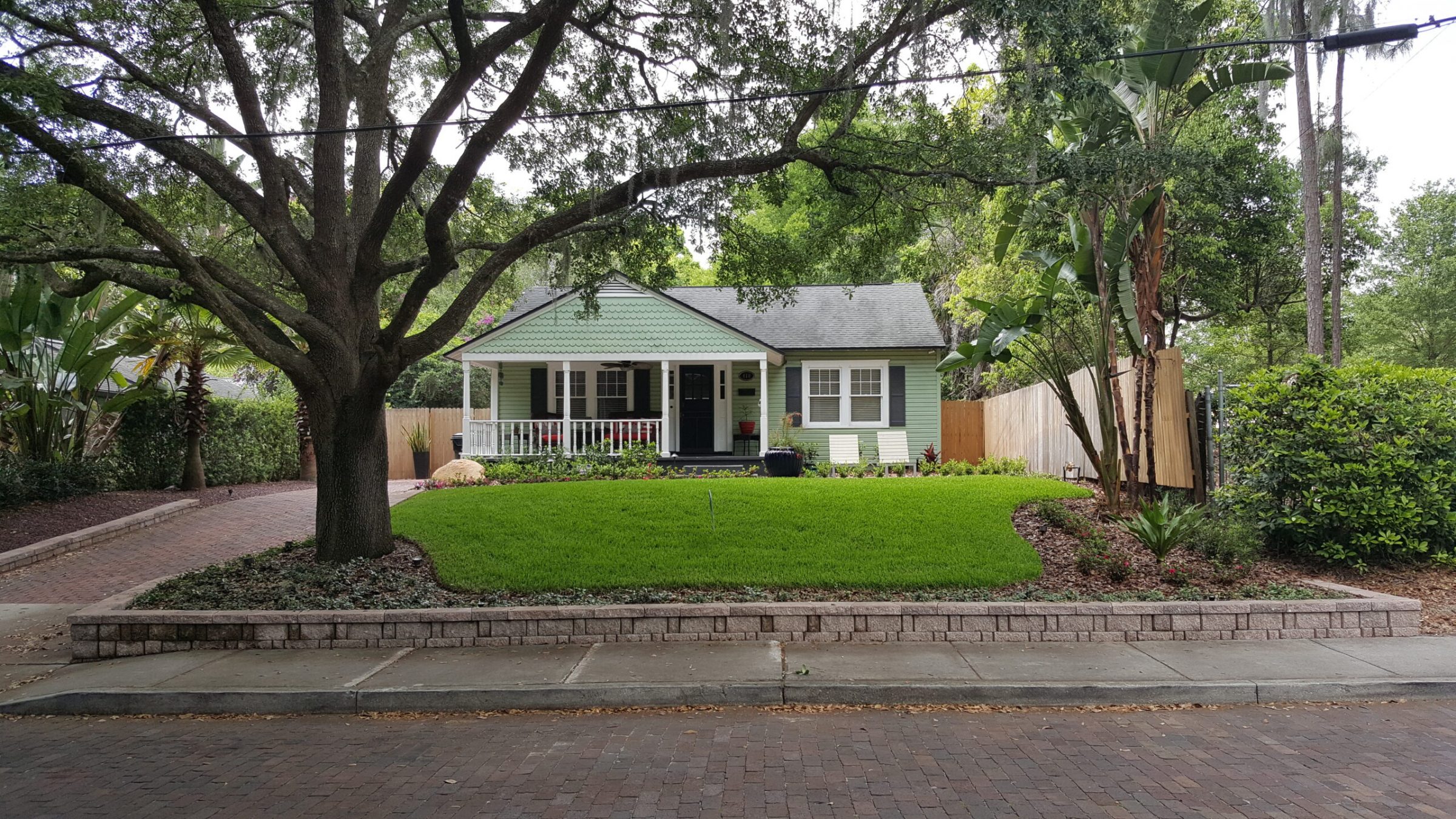 Green house with large tree and lawn
