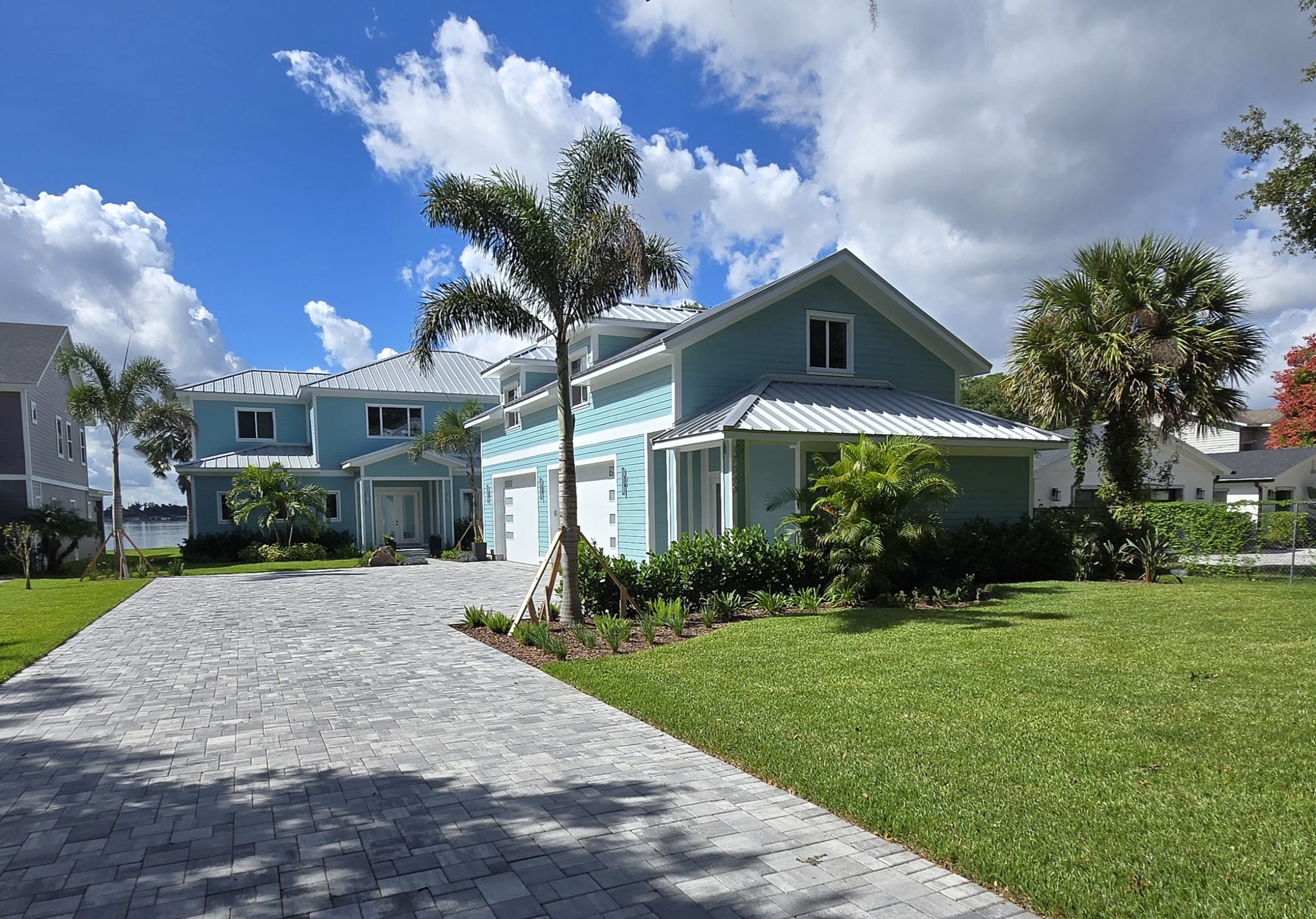 Modern blue houses with palm trees and driveway.